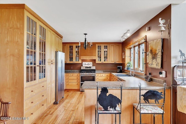 kitchen featuring light hardwood / wood-style flooring, kitchen peninsula, sink, a breakfast bar, and appliances with stainless steel finishes