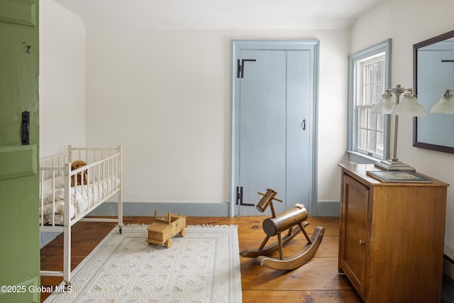 bedroom featuring light wood-type flooring and a nursery area