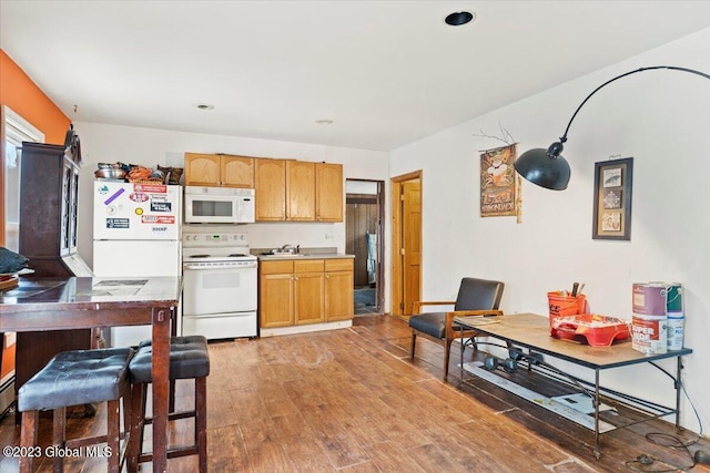 kitchen with wood-type flooring, white appliances, and sink