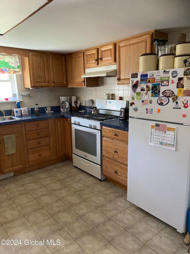 kitchen featuring backsplash, white appliances, and light tile floors