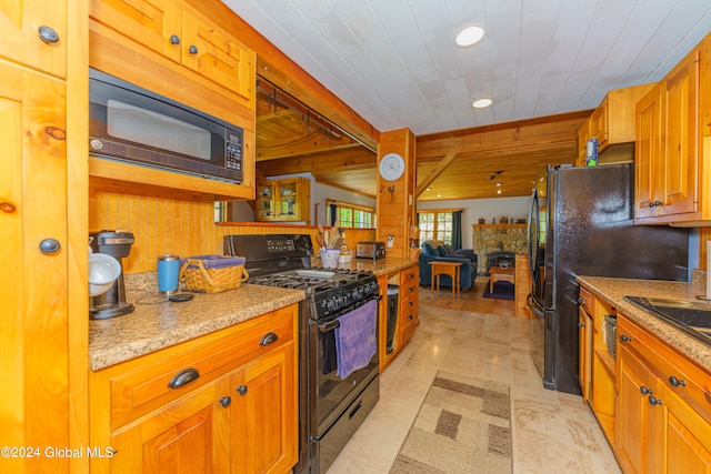 kitchen with light stone countertops, beam ceiling, black appliances, and light tile floors