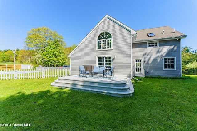 rear view of property with a wooden deck and a lawn