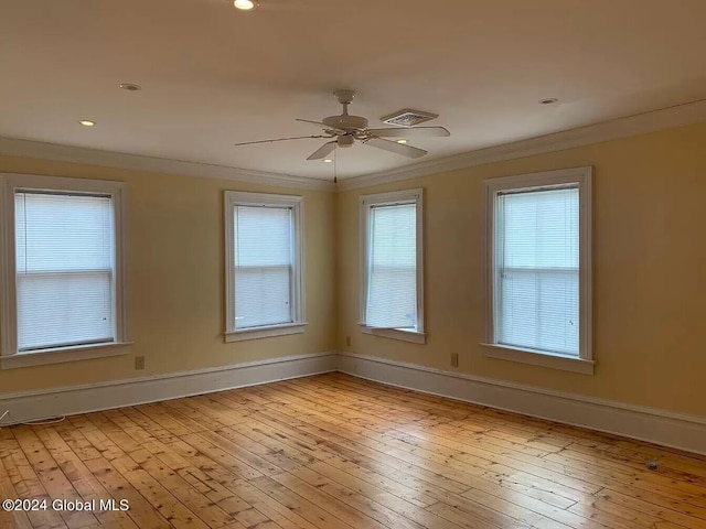 empty room with ceiling fan, plenty of natural light, light hardwood / wood-style flooring, and crown molding