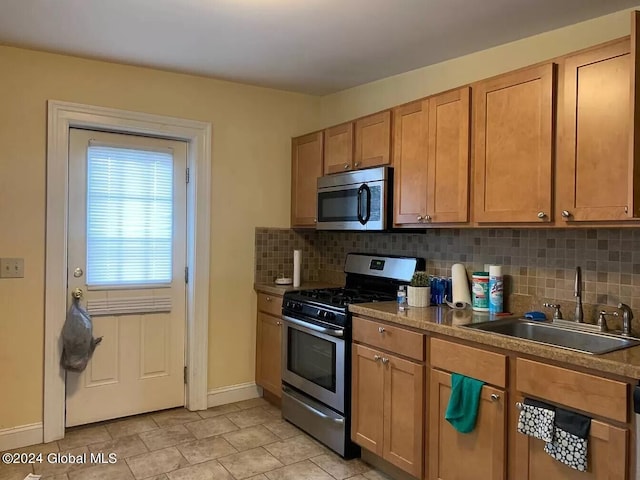 kitchen with appliances with stainless steel finishes, sink, backsplash, and light tile flooring