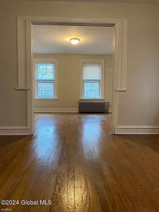 unfurnished room with dark hardwood / wood-style floors and radiator