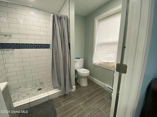 bathroom with a shower with curtain, toilet, and baseboard heating