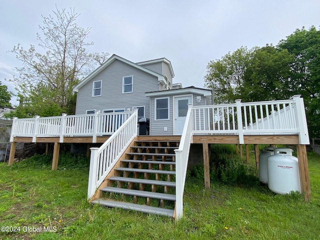 rear view of house featuring a wooden deck and a lawn