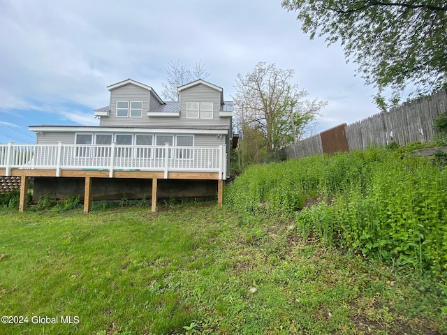 rear view of house featuring a wooden deck and a yard