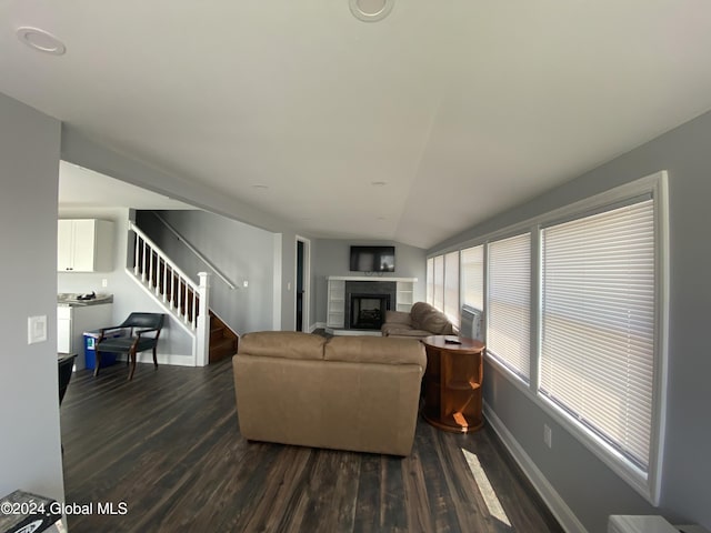 living room featuring a tile fireplace, lofted ceiling, and dark hardwood / wood-style flooring