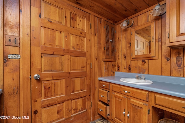 bathroom with wood walls, vanity, and wooden ceiling