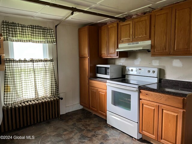 kitchen with electric stove, dark tile flooring, and radiator