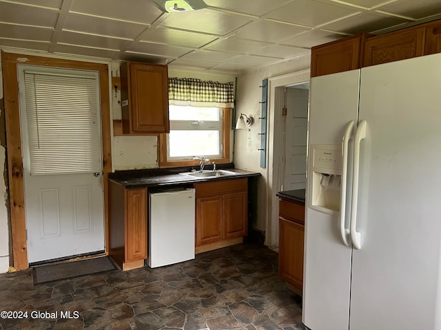 kitchen featuring dark tile floors, sink, dishwasher, and white refrigerator with ice dispenser