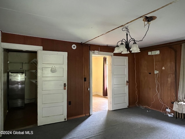 interior space featuring a notable chandelier, carpet, and black refrigerator