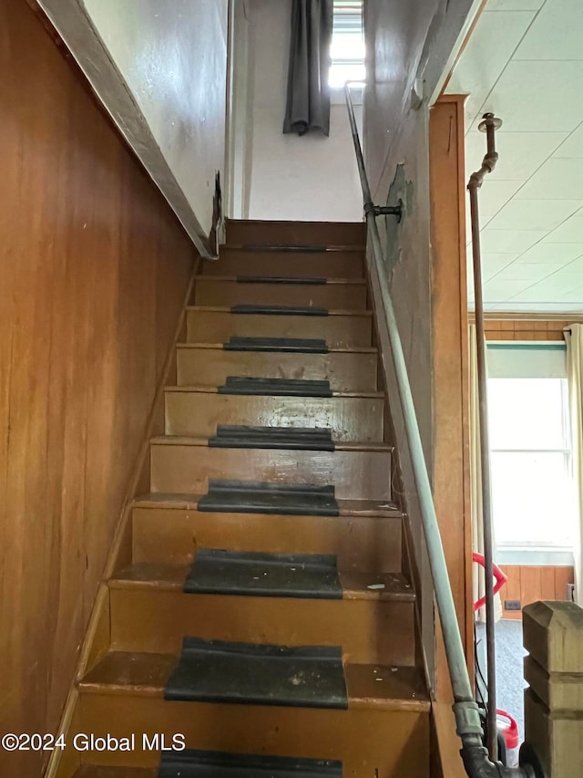 stairway featuring wood walls