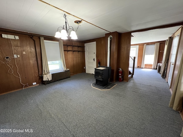 16603 State Route 22, Putnam, NY 12861 - unfurnished living room with radiator heating unit, carpet, wooden walls, a wood stove, and a chandelier