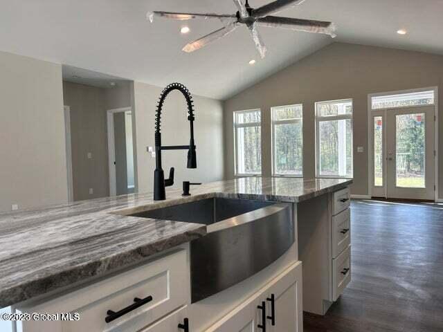 kitchen featuring white cabinets, plenty of natural light, ceiling fan, and light stone counters