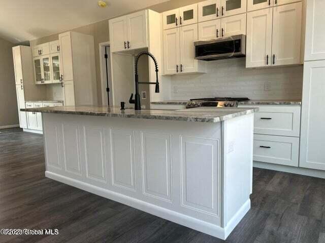 kitchen with a center island with sink, white cabinetry, and dark wood-type flooring