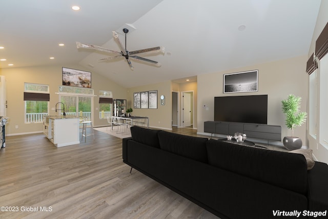 living room with ceiling fan, high vaulted ceiling, and light wood-type flooring