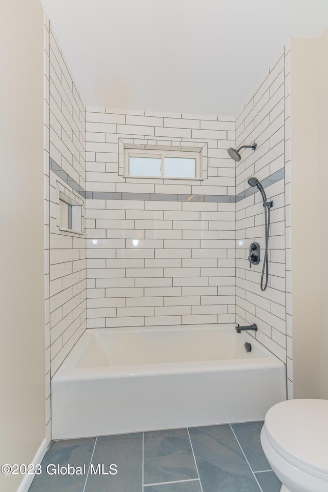 bathroom featuring tile patterned flooring, toilet, and tiled shower / bath