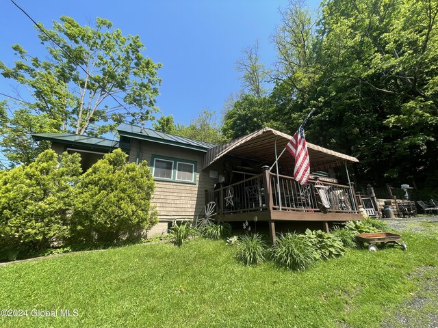 rear view of house featuring a wooden deck and a yard