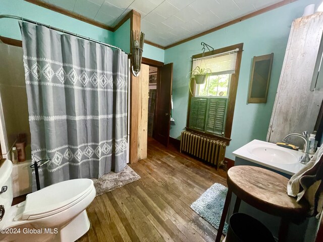 bathroom with toilet, ornamental molding, radiator heating unit, wood-type flooring, and vanity