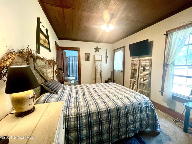 bedroom with ceiling fan, multiple windows, connected bathroom, and wood ceiling