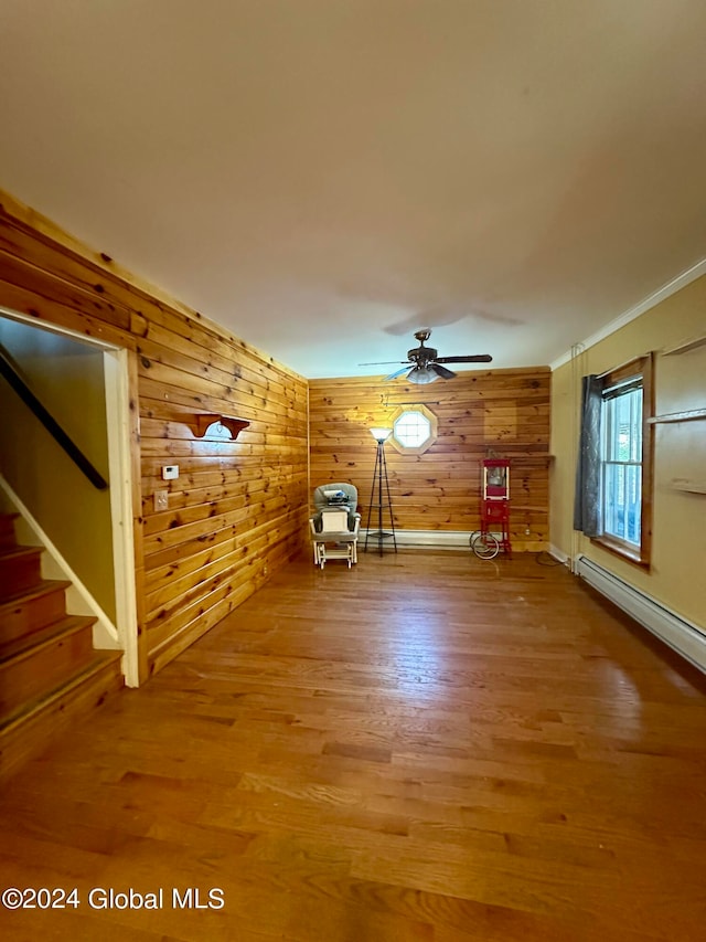 unfurnished living room featuring ceiling fan, wood walls, and hardwood / wood-style flooring