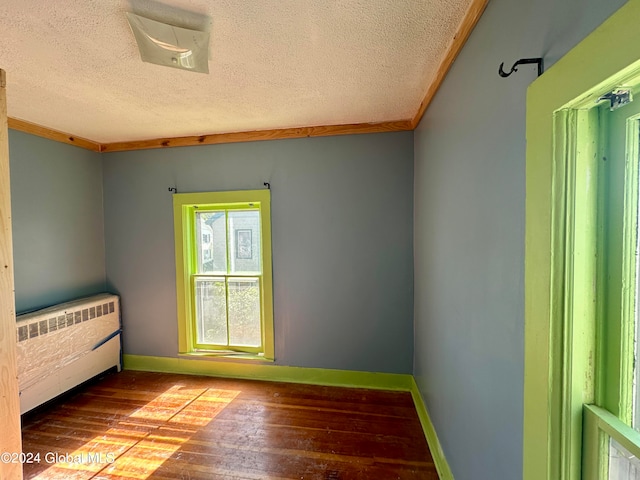 unfurnished bedroom with crown molding, a textured ceiling, radiator heating unit, and hardwood / wood-style floors