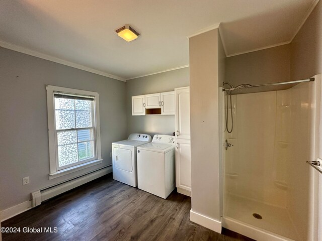 clothes washing area featuring washing machine and clothes dryer, crown molding, dark wood-type flooring, a baseboard heating unit, and cabinets