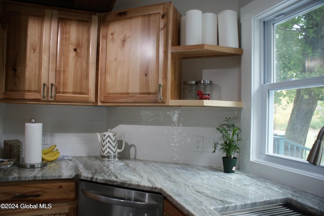 kitchen featuring stainless steel dishwasher, light stone countertops, and backsplash