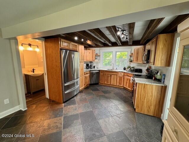 kitchen featuring beamed ceiling, sink, and stainless steel appliances