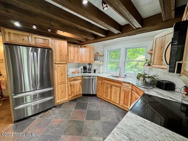 kitchen with sink, decorative backsplash, light stone countertops, appliances with stainless steel finishes, and beam ceiling