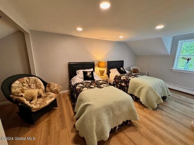 bedroom with light hardwood / wood-style floors, lofted ceiling, and a baseboard heating unit