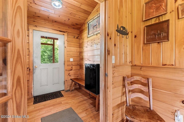 entryway with wooden walls, vaulted ceiling, light wood-type flooring, and wooden ceiling