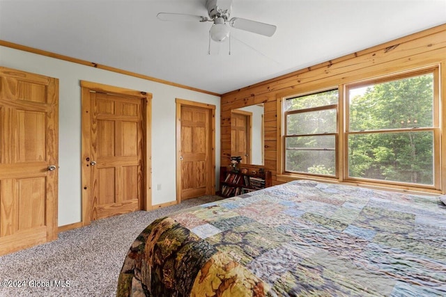 bedroom featuring ceiling fan, wood walls, and carpet flooring