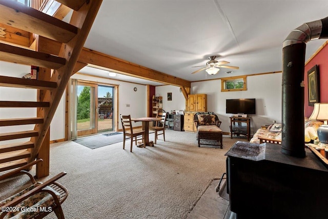 carpeted living room featuring ceiling fan and a wood stove