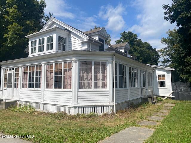 view of property exterior featuring a lawn and a sunroom