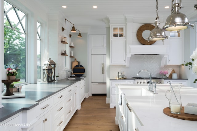 kitchen featuring paneled built in refrigerator, a healthy amount of sunlight, range hood, and pendant lighting