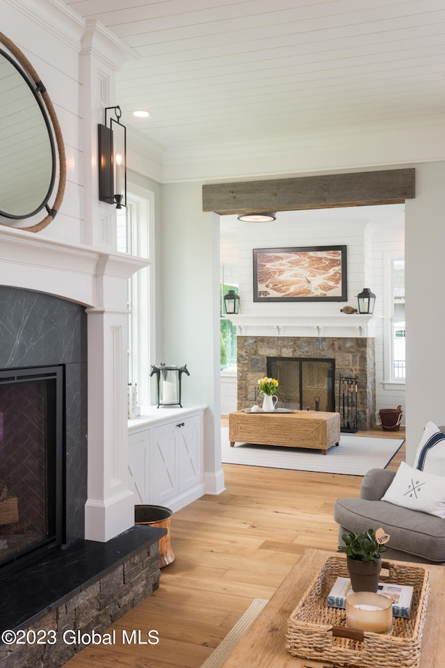 living room featuring ornamental molding, a stone fireplace, and hardwood / wood-style flooring