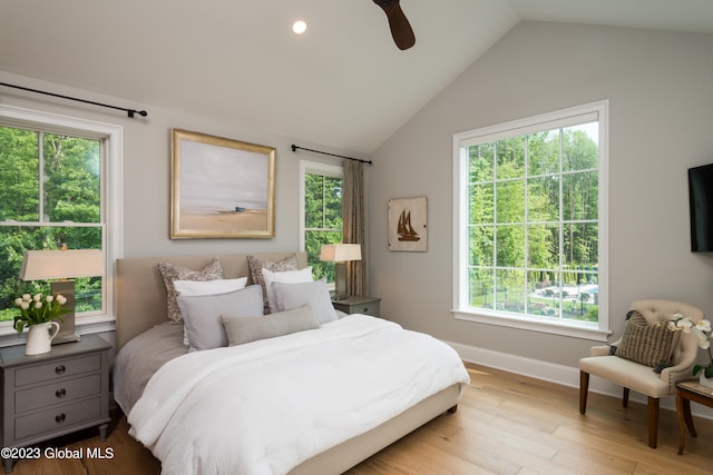 bedroom featuring ceiling fan, vaulted ceiling, multiple windows, and light wood-type flooring