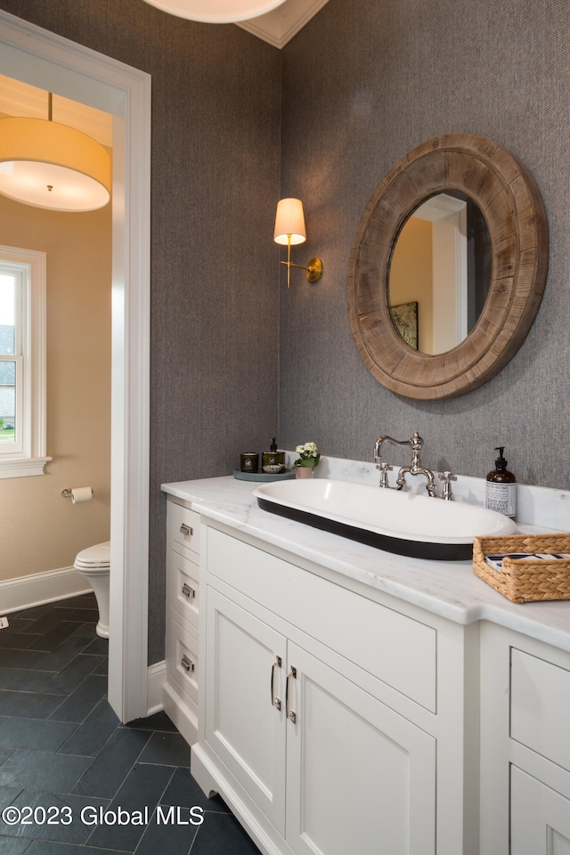 bathroom with toilet, crown molding, vanity, and tile patterned floors