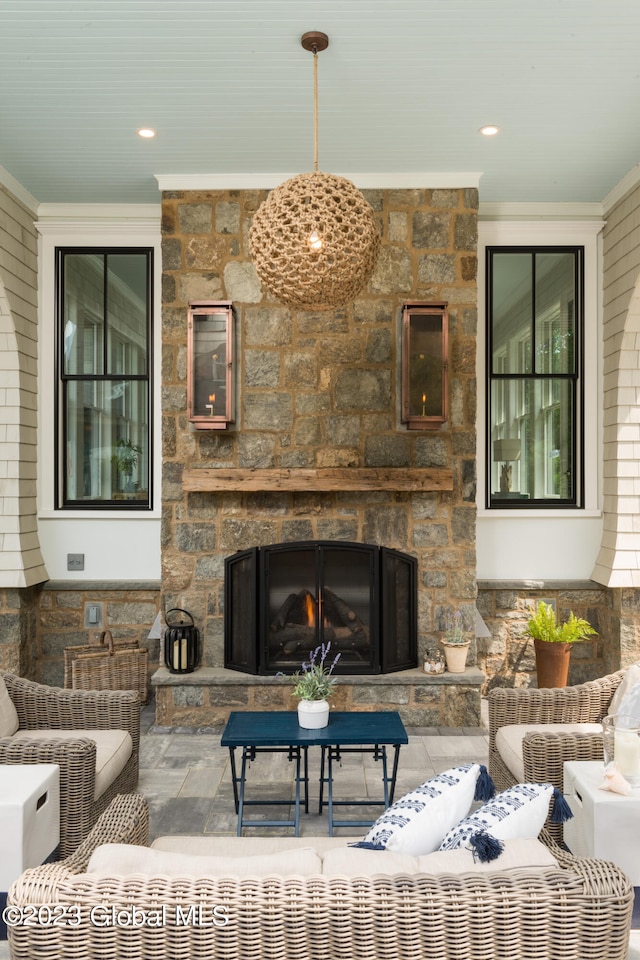 living room with a stone fireplace and crown molding