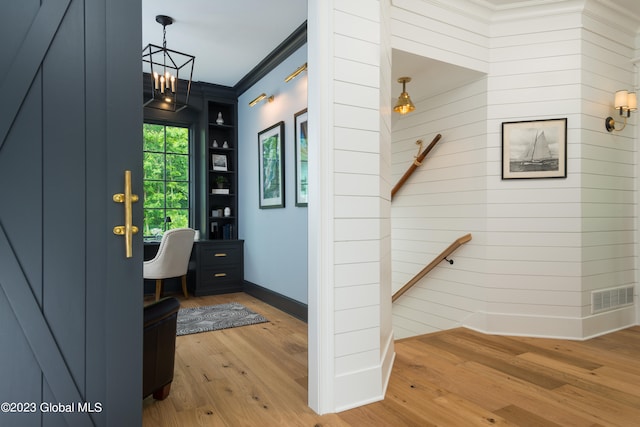 entryway featuring crown molding, hardwood / wood-style flooring, and an inviting chandelier