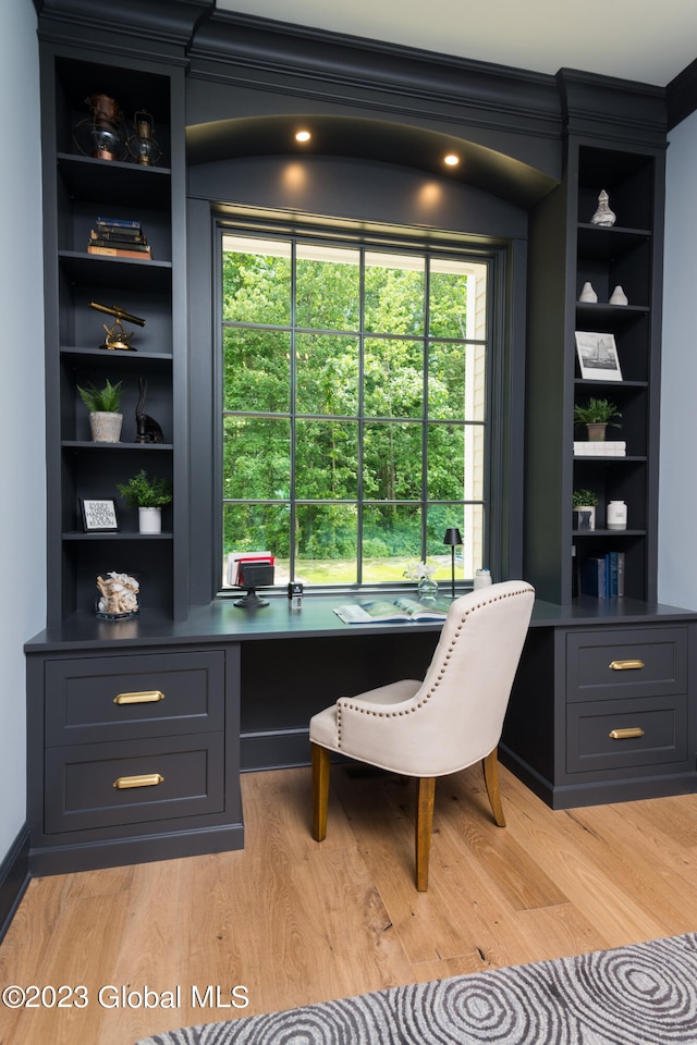 office featuring built in desk, ornamental molding, built in shelves, and light hardwood / wood-style floors