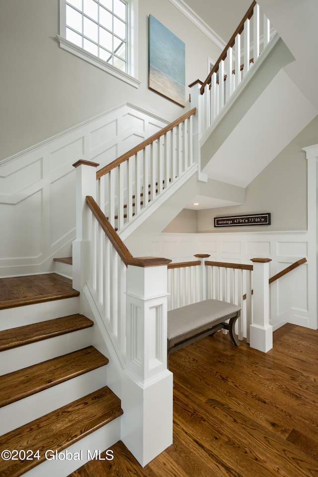 stairs with crown molding, hardwood / wood-style floors, and ornate columns