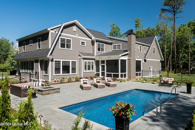 back of house featuring a sunroom, a patio area, an outdoor living space with a fire pit, and a fenced in pool