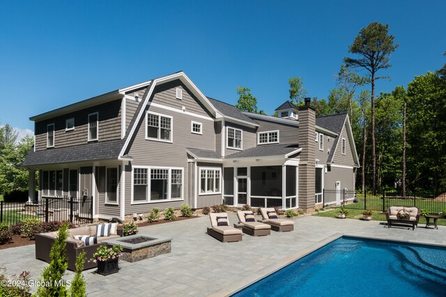 rear view of house with an outdoor living space with a fire pit, a patio, a fenced in pool, and a sunroom