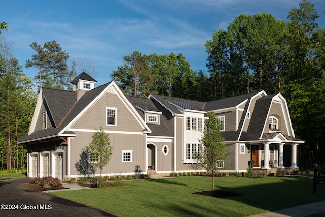 view of front of property with a front yard, a garage, and a porch