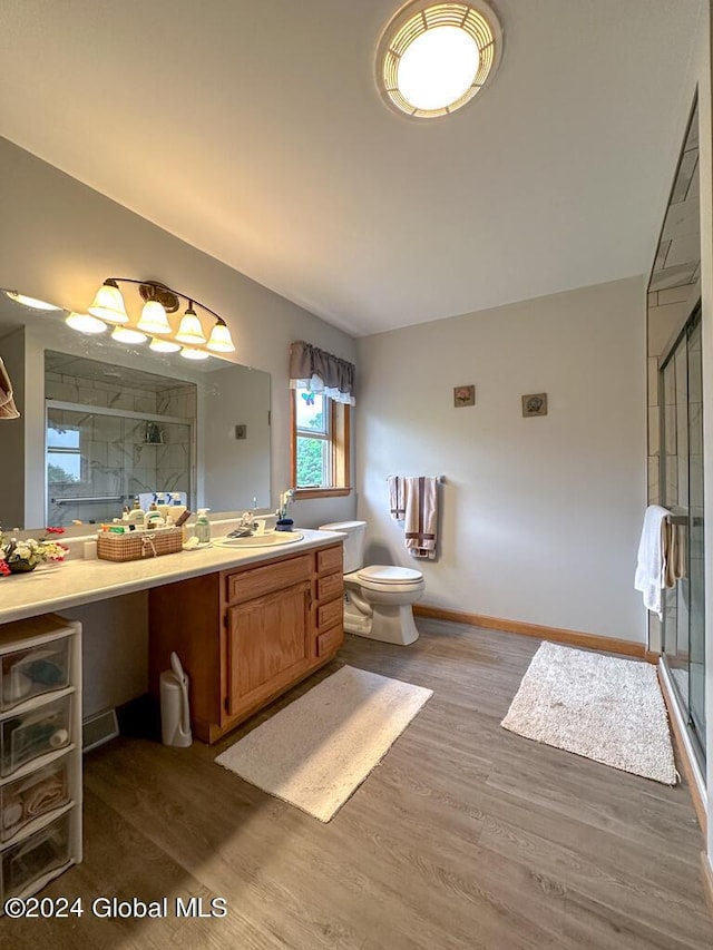 bathroom with toilet, vanity, an enclosed shower, and hardwood / wood-style flooring