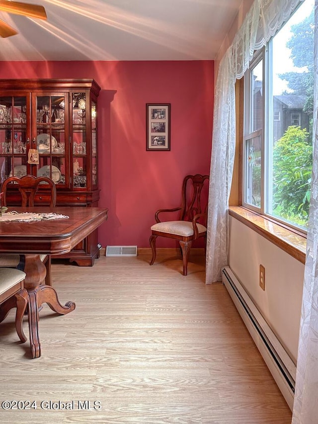 living area with a wealth of natural light, light hardwood / wood-style flooring, and a baseboard radiator